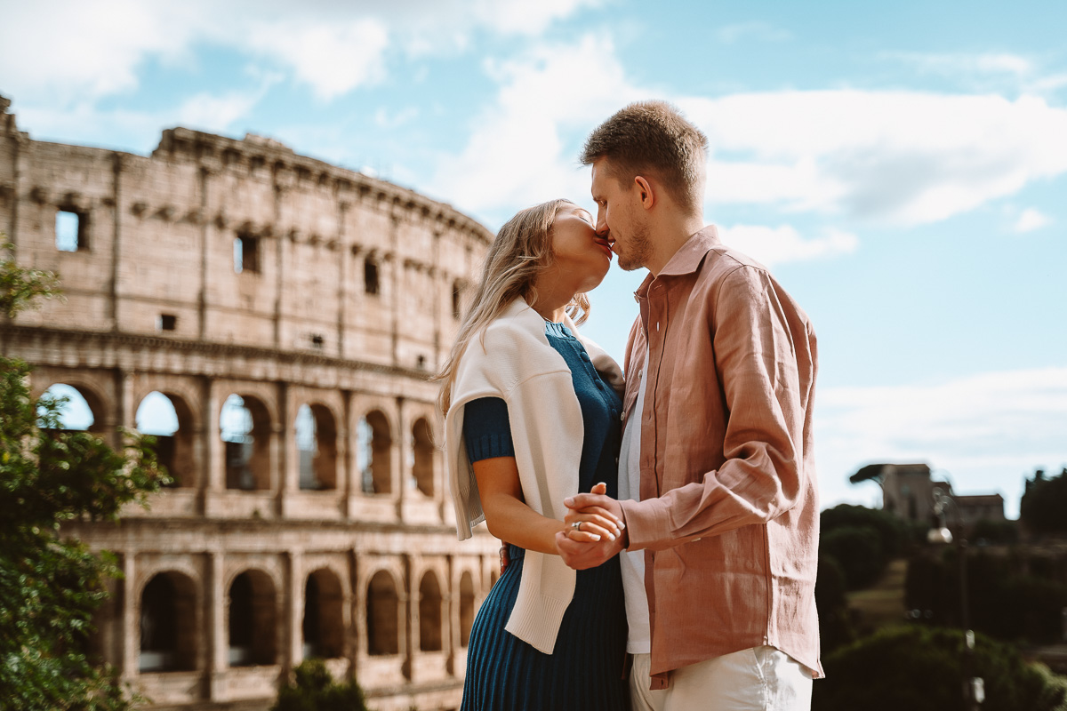 a man and woman hugging in front of colosseum