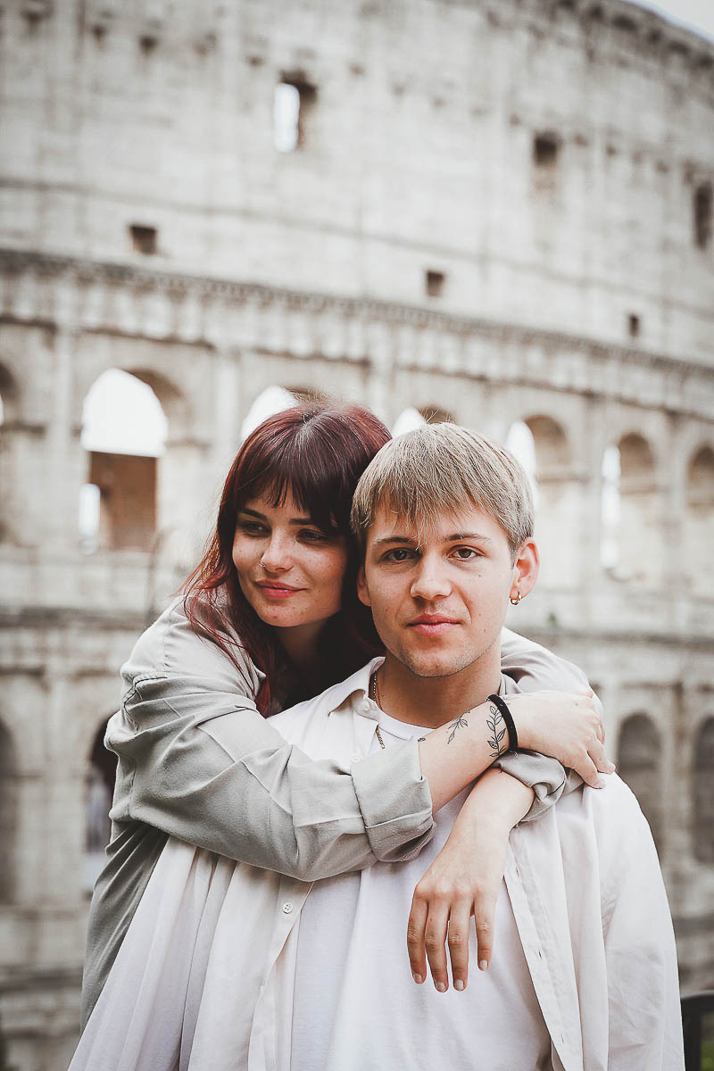 a man and woman hugging in front of ath colosseum