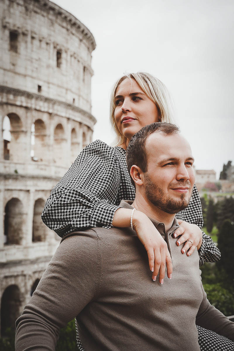 a man and woman hugging in front of colosseum